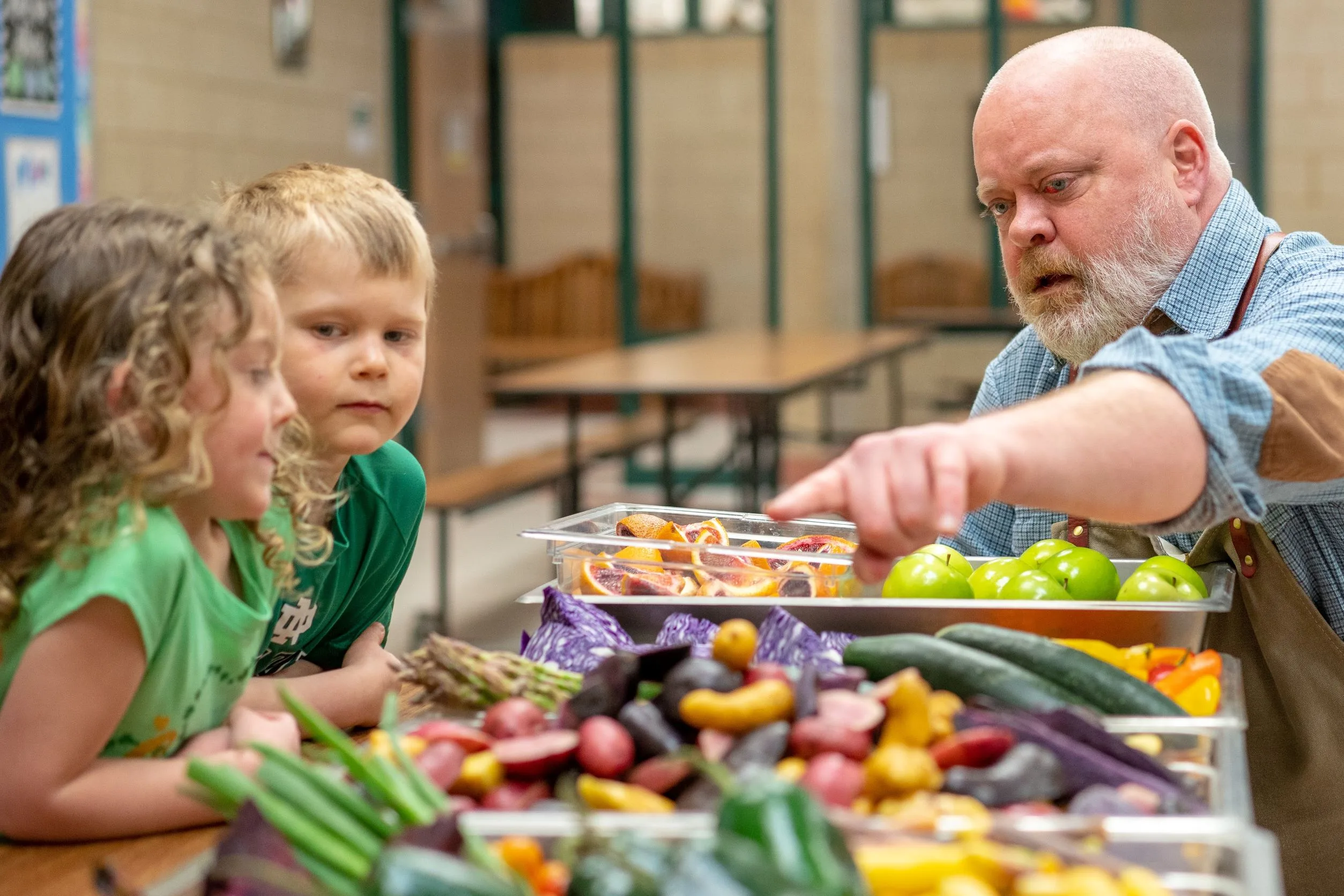 A Chef points out colorful vegetables to children.