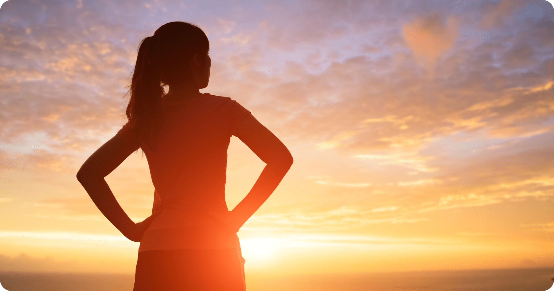 Silhouetted woman gazing at a sunrise
