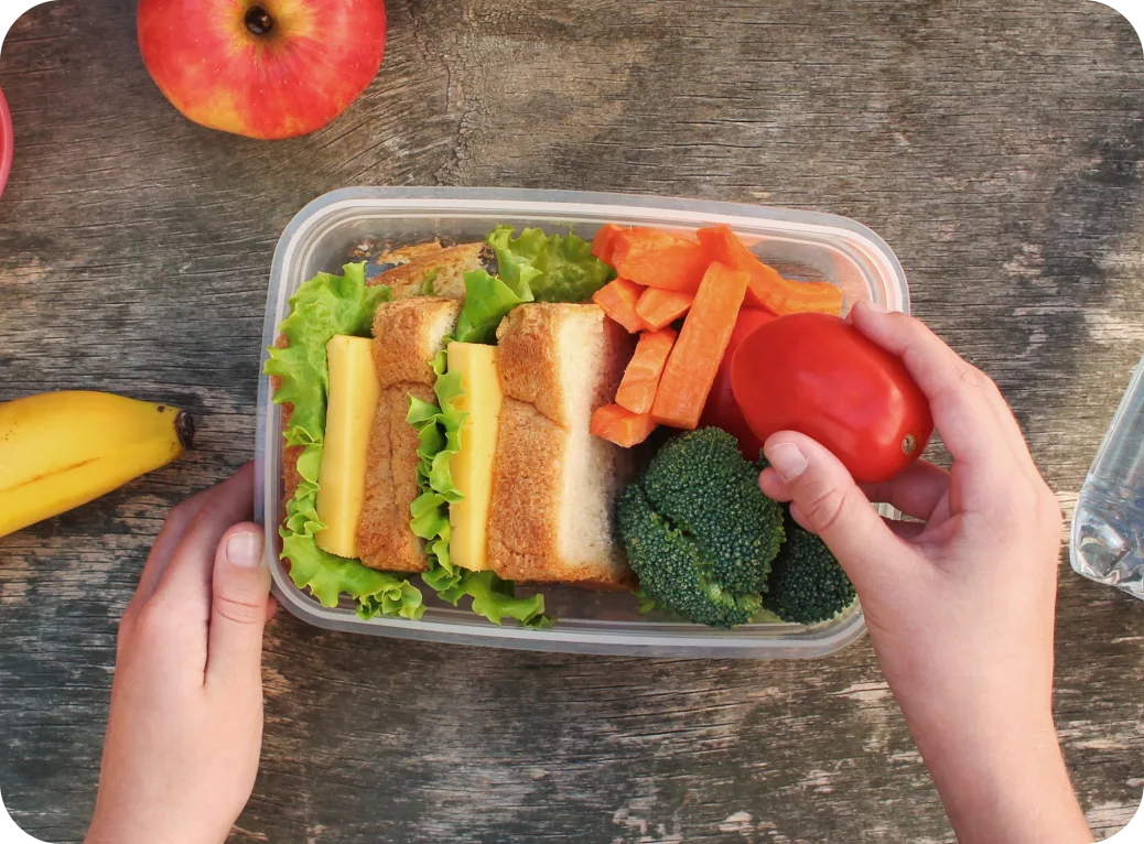 Lunchbox with sandwiches, tomatoes, carrots, and broccoli.