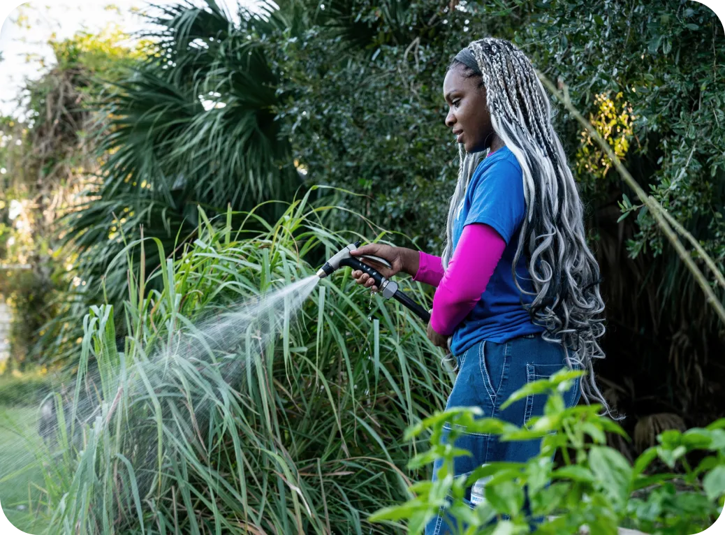 A young person waters plants at the farm.