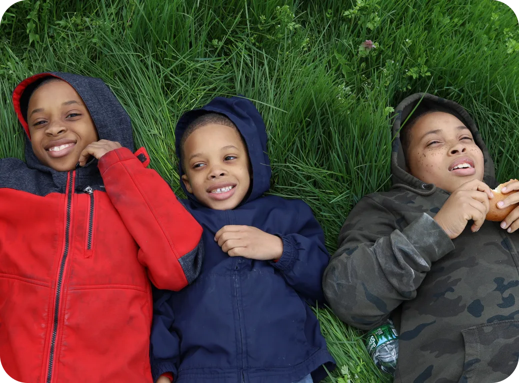 Three young children lay in the grass.