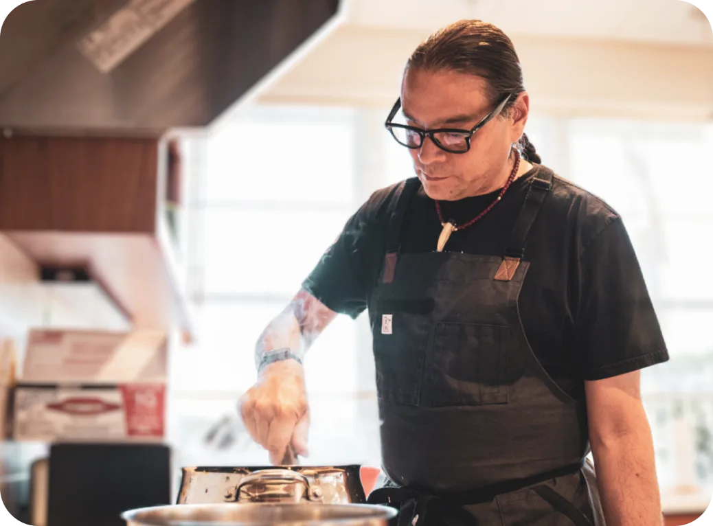 Sean Sherman cooks at a stove.