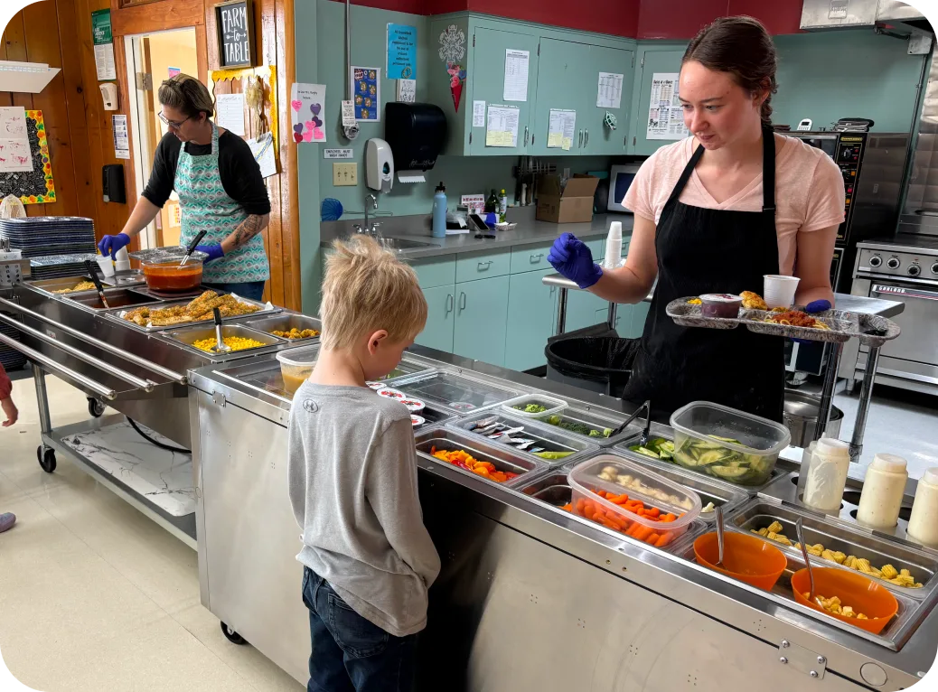 A child stands before a salad bar at school.