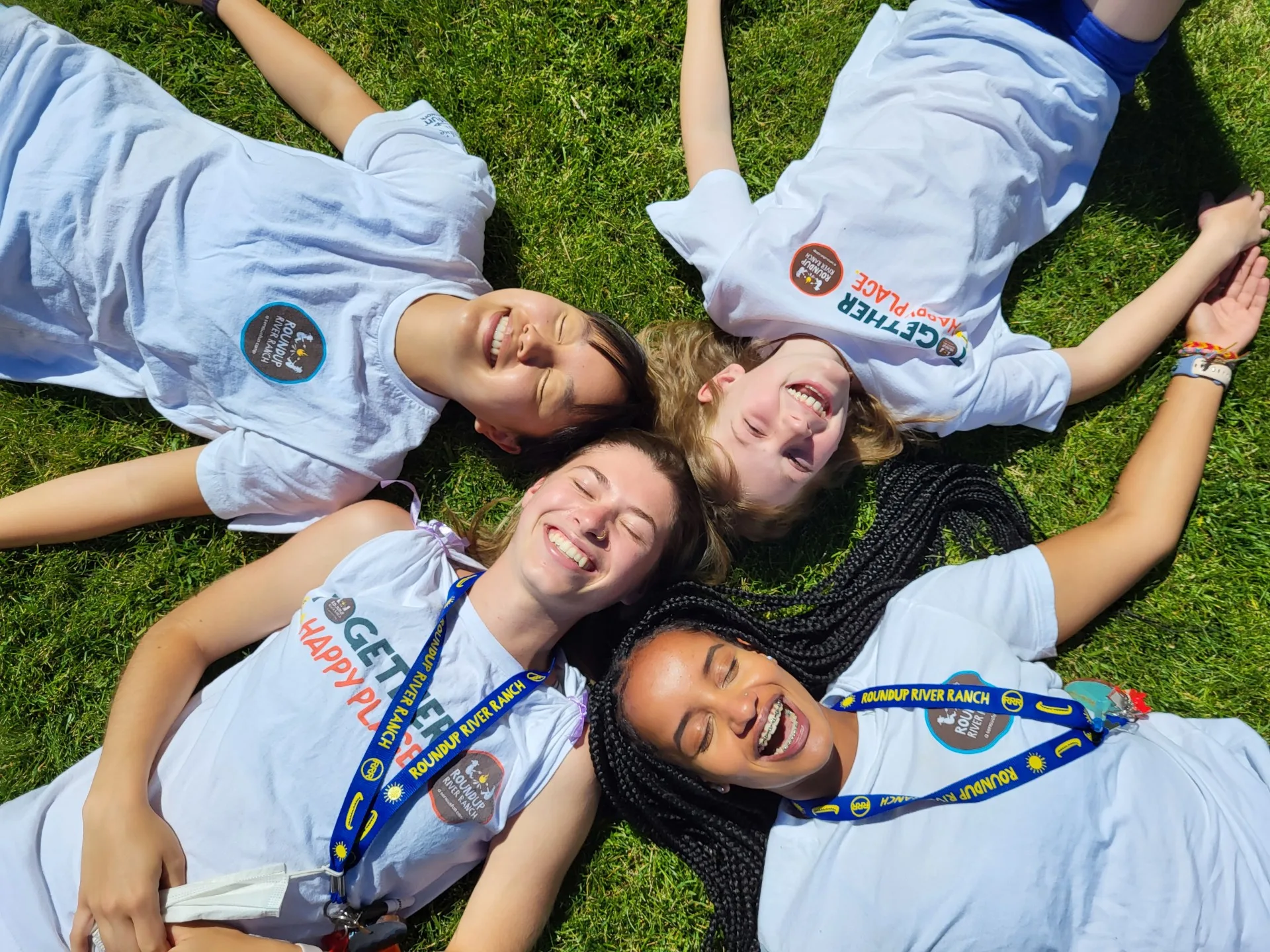 Kids lay on the grass, smiling in the sunshine.
