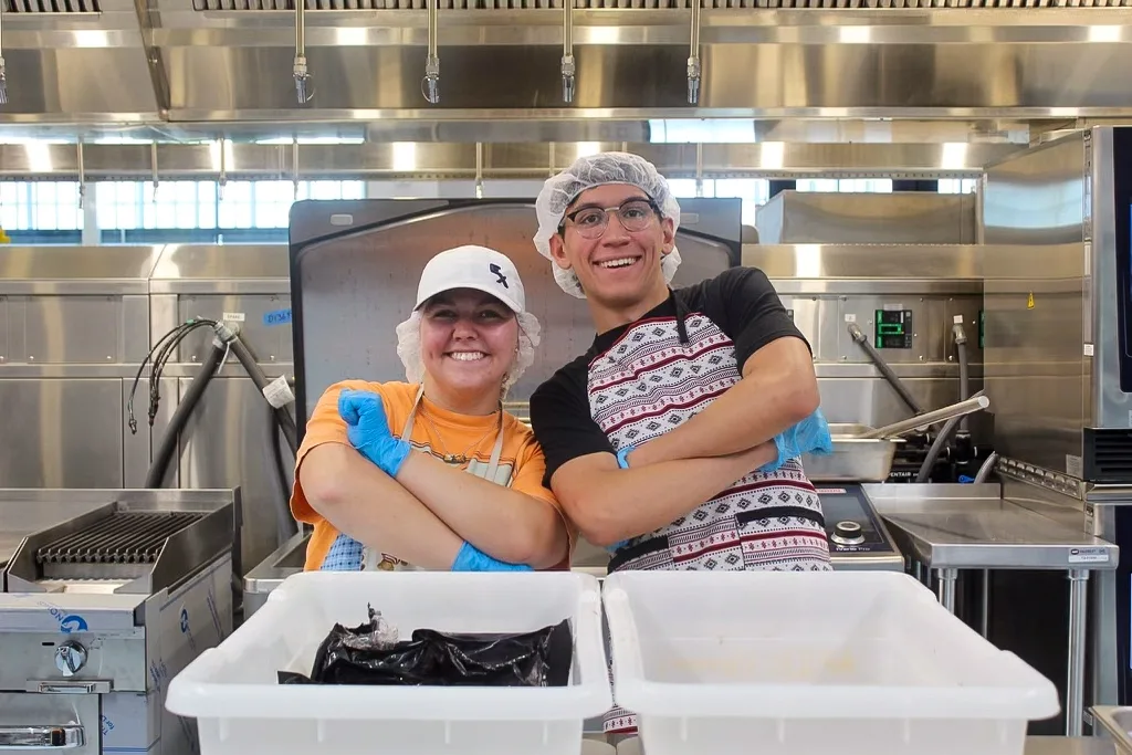 Two young people in hairnets stand in the kitchen at the Native Youth in Food and Agriculture Leadership Summit