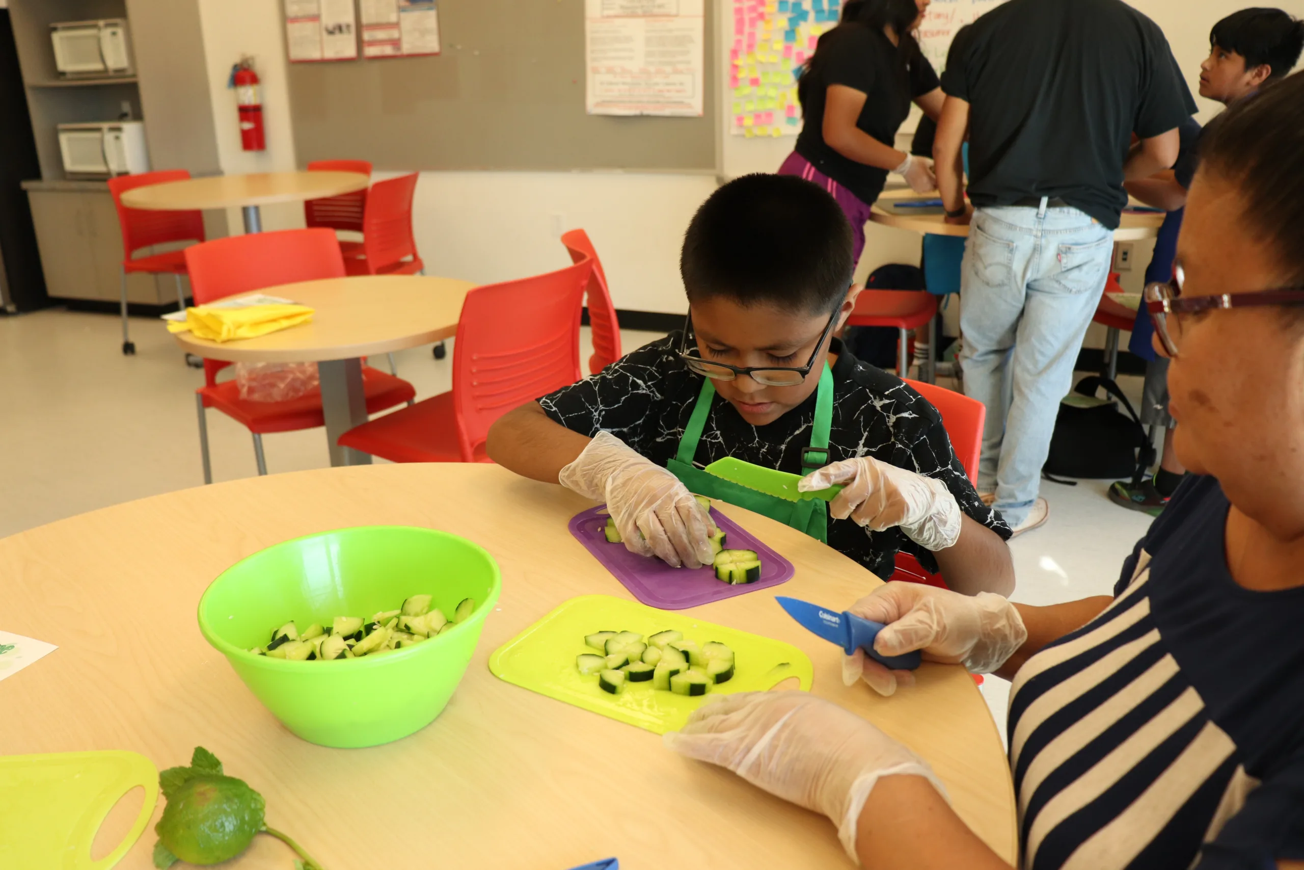 A child cuts cucumbers with a small knife.