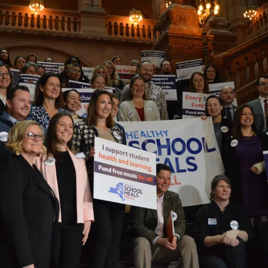 Leaders holding signs supporting school meals for all in New York