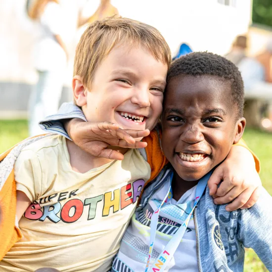 Two young kids smiling with their arms around each other