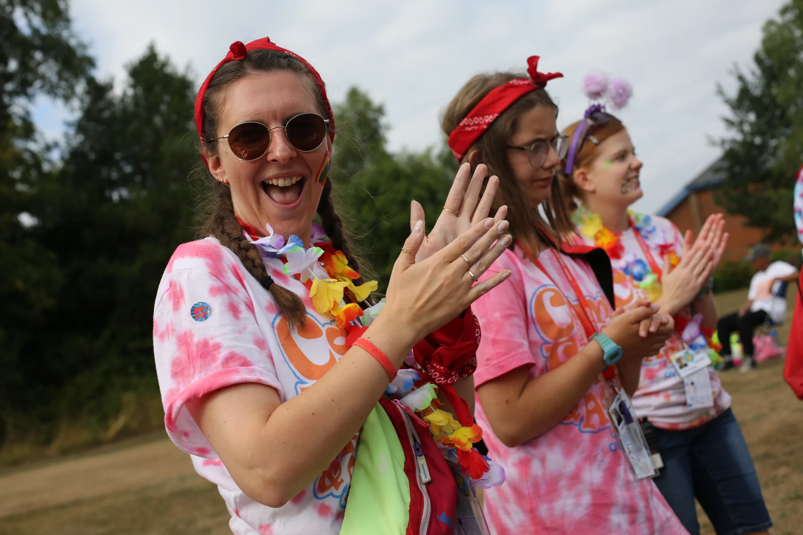 Young person clapping in sunglasses and pink tie dye shirt