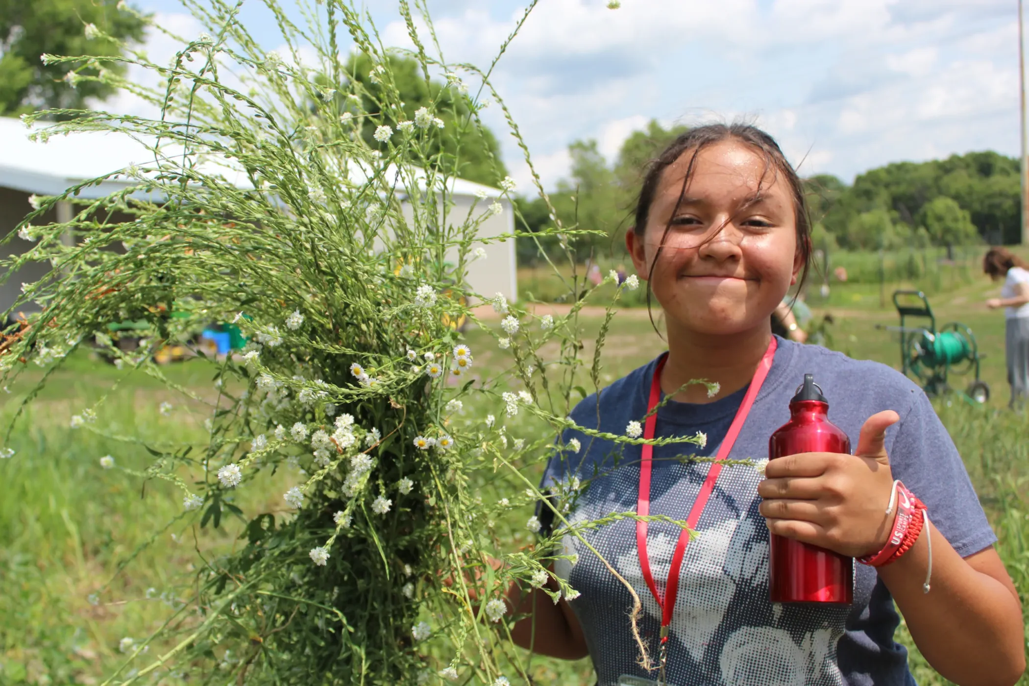 A young person holding flowering herbs.