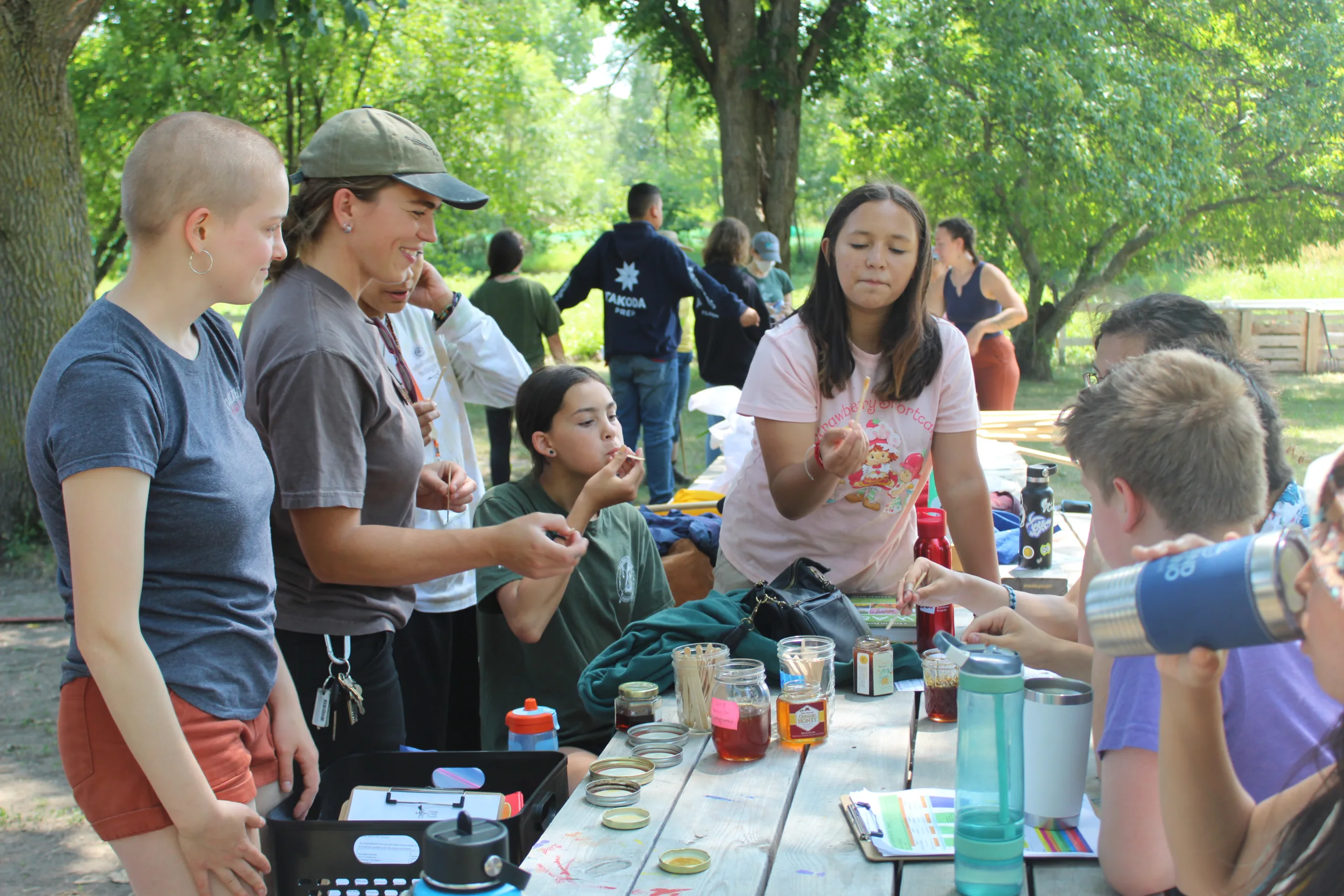 Youth at a picnic table sampling food.