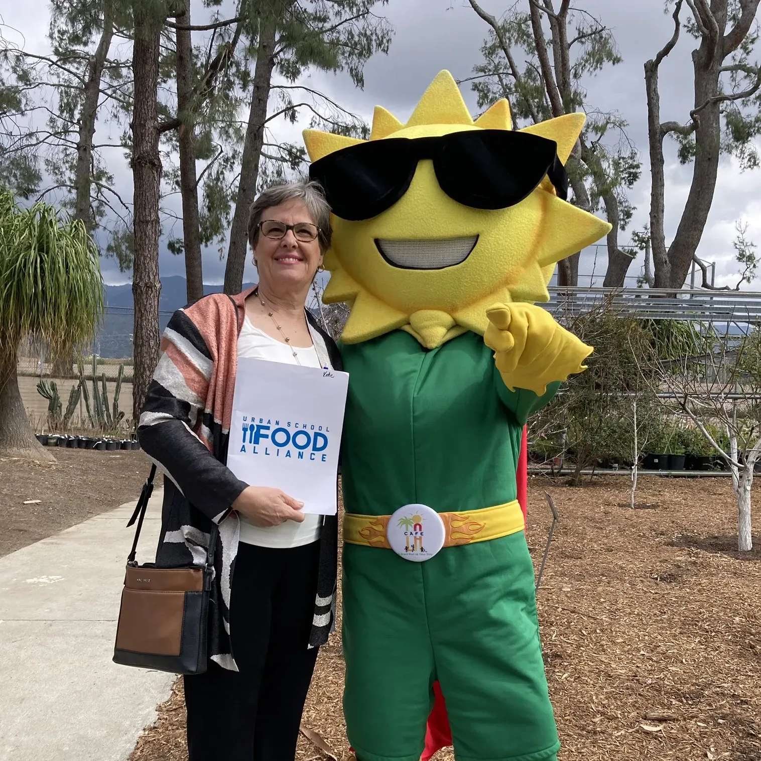 Katie Wilson stands with Urban School Food Alliance's mascot.