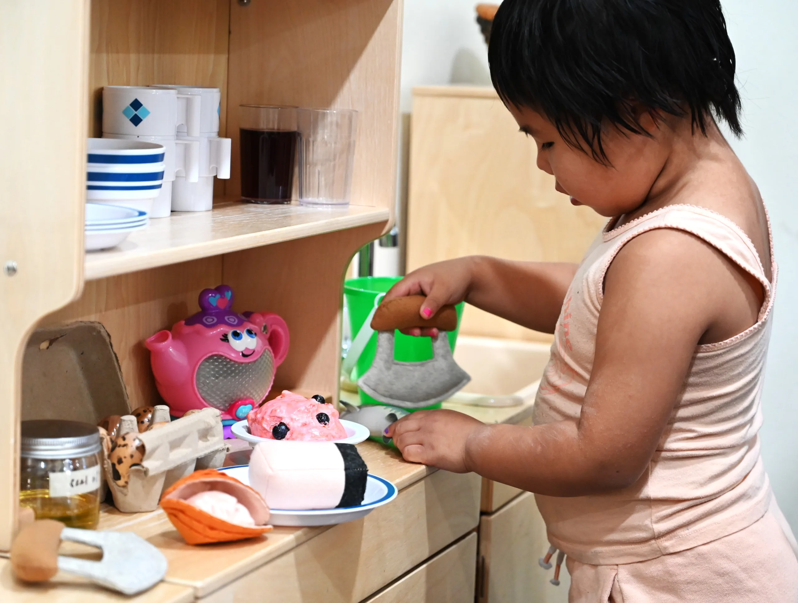A child using a traditional food preparation toy.